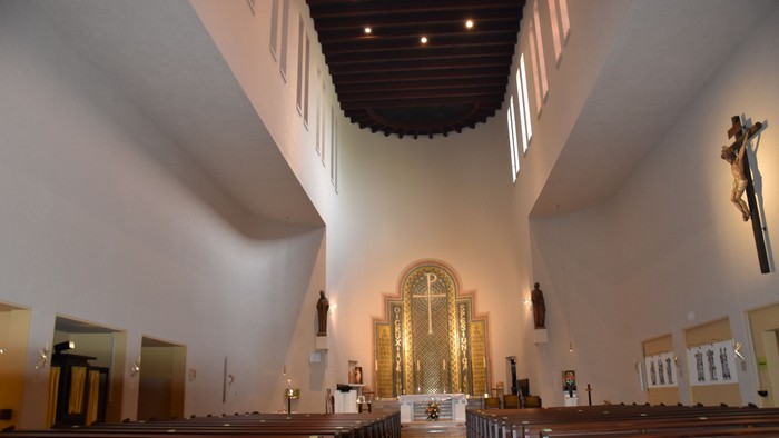 Innenraum einer Kirche mit hölzernen Kirchenbänken und hohem Gewölbedach