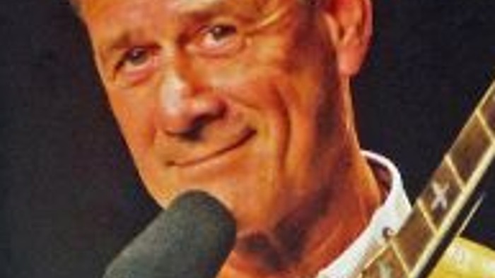 Ein Mann spielt Gitarre und singt in ein Mikrofon