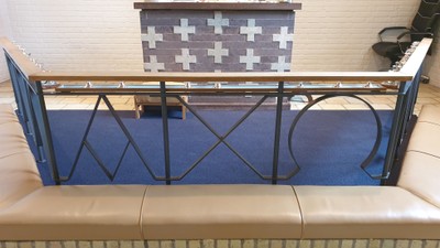 En blå balustrade med sort jernarbejde foran en hvid køkkenbord med sorte og hvide tæpper.