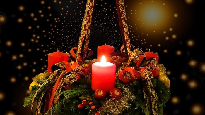 Ein Adventskranz mit einer brennenden Kerze hängt an einem Band