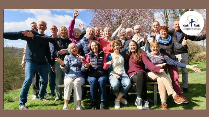 Eine Gruppe von Menschen posiert fröhlich im Freien unter blühenden Bäumen