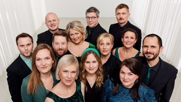 Gruppe af mennesker, der poser til et foto, klædt formelt i jakkesæt og kjoler.