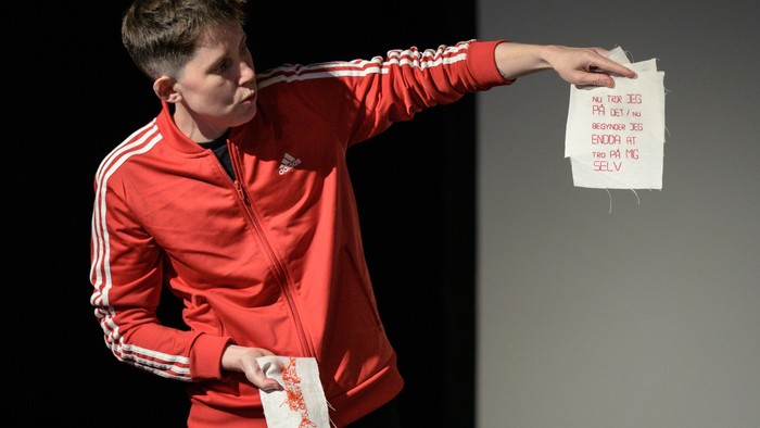 En person i rød sportssjakal holder op og papir med noter.