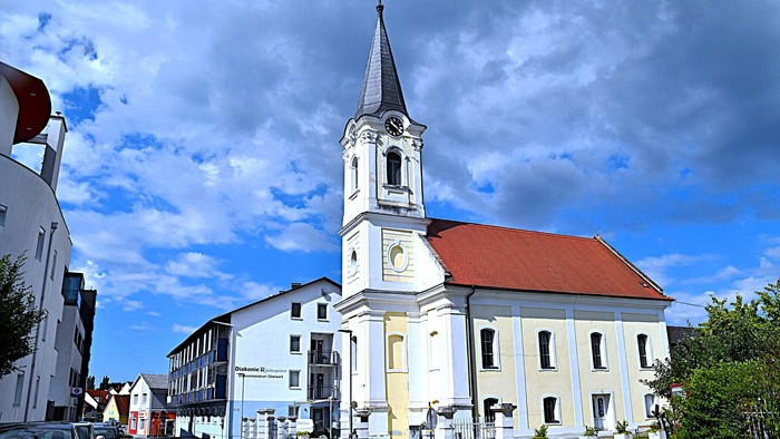 Kirchengemeinde mit weißem Turm und rotem Dach in kleiner Stadt