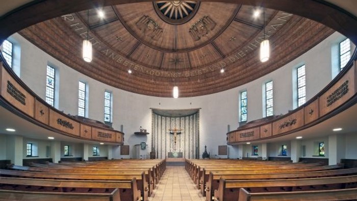 Große, helle Kirche mit Kuppeldecke und Holzbänken