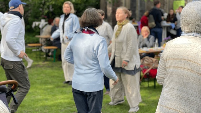 Eine Gruppe älterer Menschen steht im Park und unterhält sich.