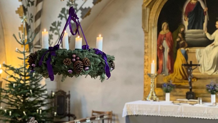 Elegant kirkealter prydet med en festlig kranselysestage, lys og religiøs kunst.