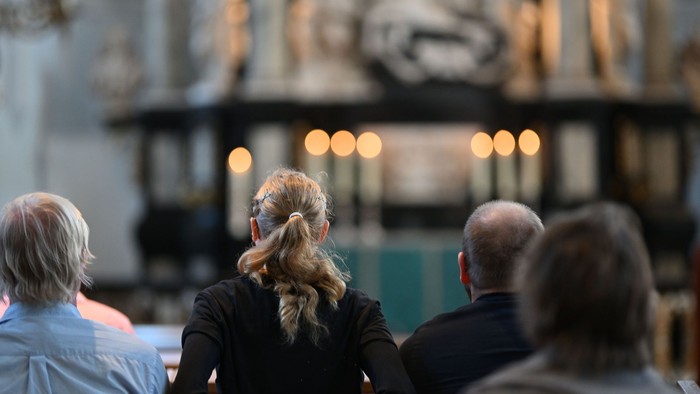 Menschen in Kirchenbänken, die aufmerksam mit Kopfhörern zuhören und sich auf eine Predigt oder einen Gottesdienst konzentrieren.