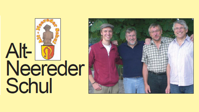 Vier Männer vor Grünfläche mit Schul-Logo