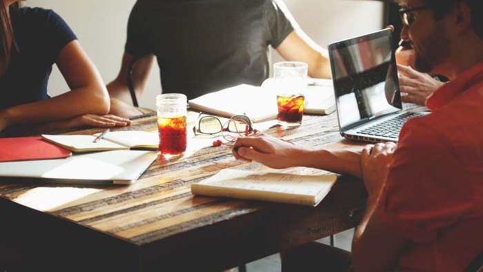 En gruppe af studerende sidder ved et bord med laptoper og noter.