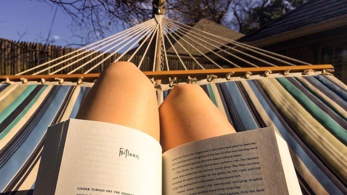 Hand hält ein offenes Buch unter einem Regenschirm.