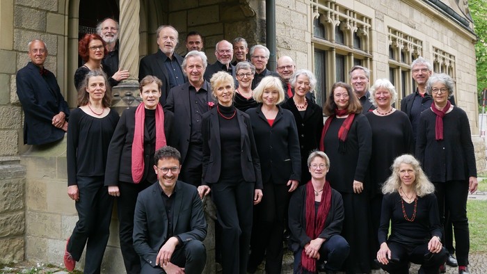 Ein Chor steht vor einem alten Gebäude und posiert für ein Gruppenfoto.
