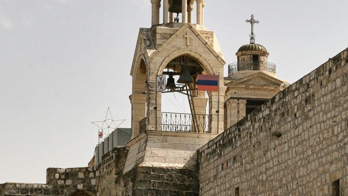 Steingebäude mit Kreuz obenauf und Flaggen.