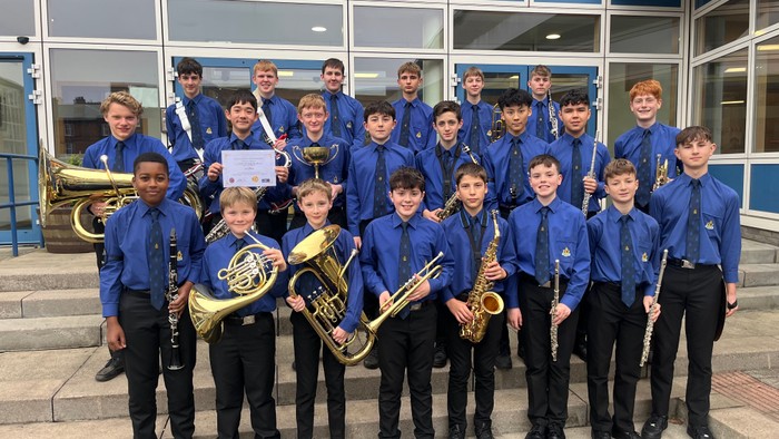 School band poses with instruments outside building