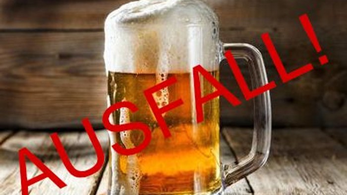 Ein Glas Bier steht auf einem Holztisch mit der Aufschrift