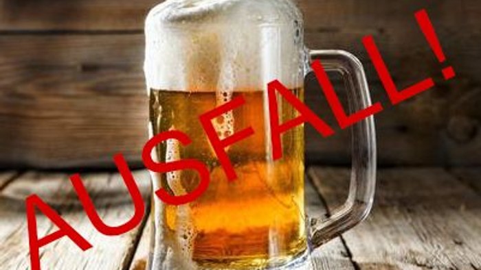 Ein Glas Bier steht auf einem Holztisch mit der Aufschrift 