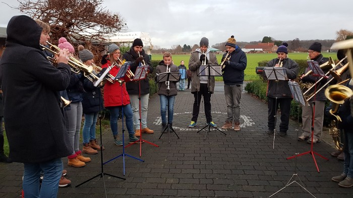 Eine Gruppe von Musikern spielt draußen verschiedene Blasinstrumente