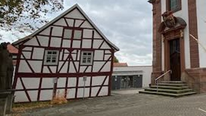Bunte Kirche mit Uhrturm und halbtimbertem Haus daneben