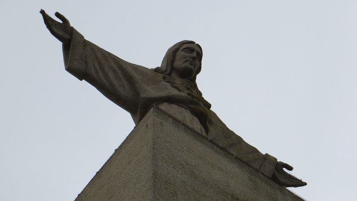 Eine Statue eines Mannes mit ausgebreiteten Armen auf einem Sockel.