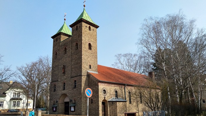 Alte Kirche mit zwei Türmen und rotem Dach an der Straße