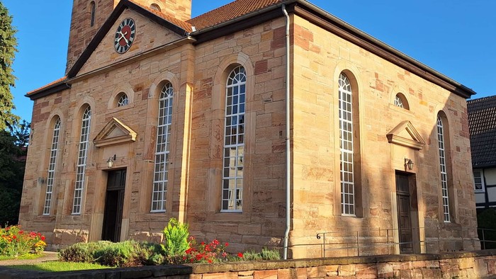 Steinerne Kirche mit hohem Turm und Bogenfenstern.