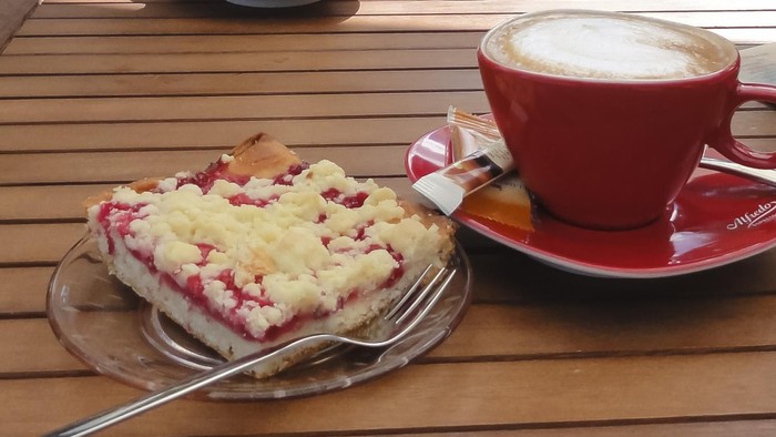 Ein Stück Kuchen und eine Tasse Kaffee auf einem Holztisch