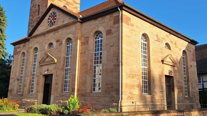 Steinerne Kirche mit hohem Turm und Bogenfenstern.