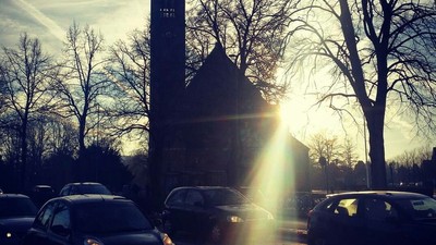 En kirke med tårn og solskin bagved.