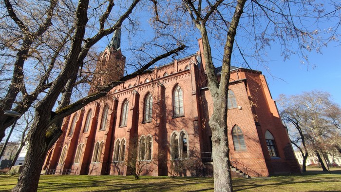 St. Gertraud von der Südostseite aus der Froschperspektive. Gotischer Backsteinbau mit Turm und Spitze.