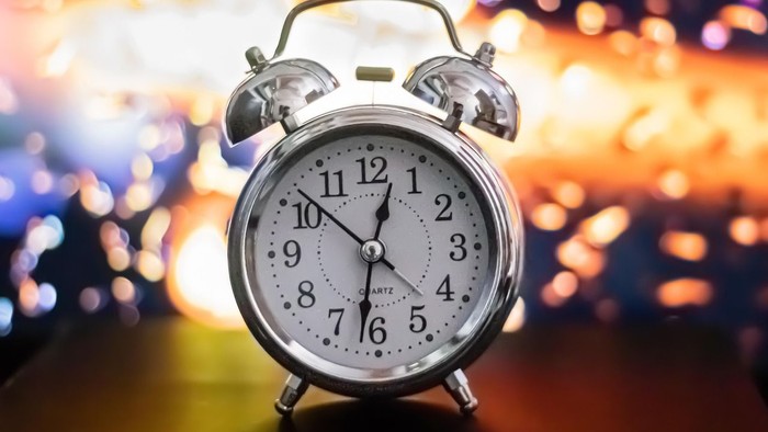 ein Wecker vor einem lichterfüllten Hintergrund