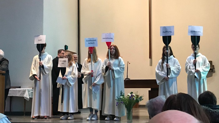 Kinder in weißen Kleidern halten Schilder und Kerzen in Kirche