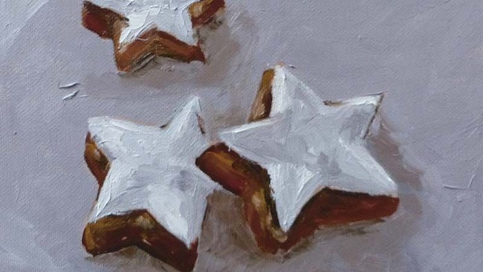 Drei sternförmige Kekse mit weißer Zuckergussglasur auf einer hellen Oberfläche.