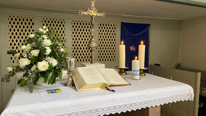 Kirchenaltar mit geöffnetem Buch, Kerzen und Blumen