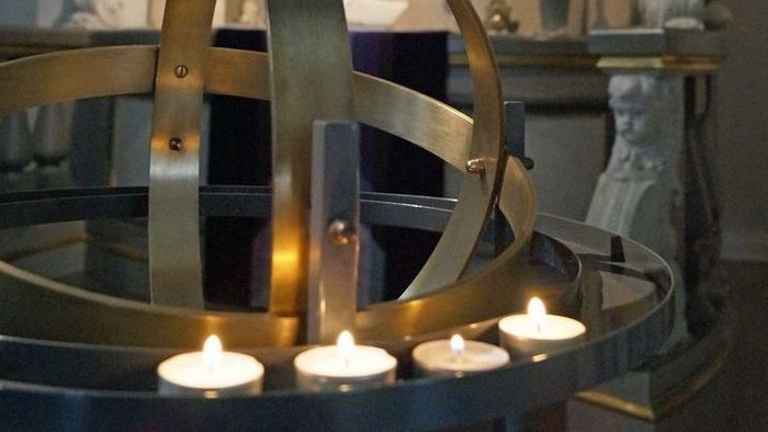 Ein metallener Globus mit brennenden Kerzen in einer Kirche
