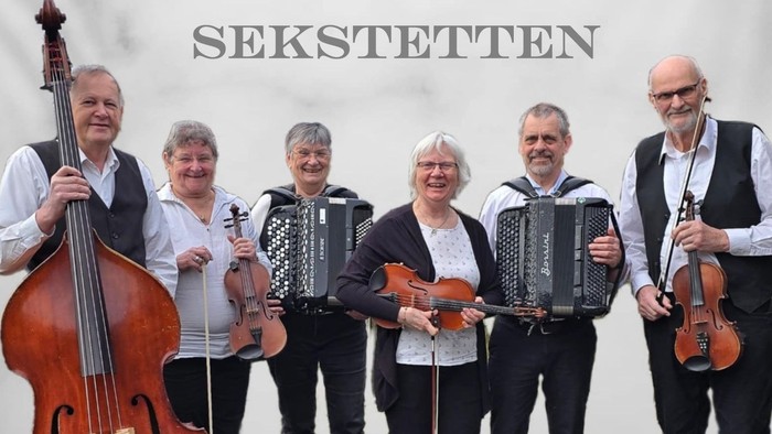 En sekstet poserer med deres musikinstrumenter