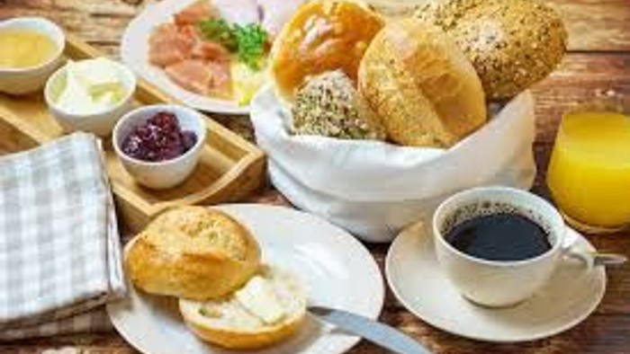 Ein Frühstücksbuffet mit verschiedenen Brotsorten, Aufstrichen, Kaffee und Saft.