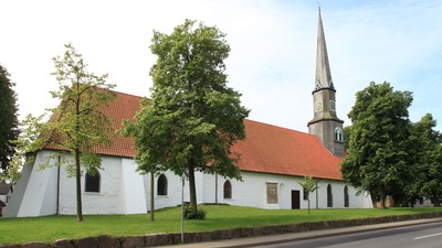 Weiße Kirche mit rotem Dach und hohem Turm neben Straße