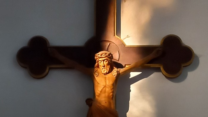 Ein hölzernes Kruzifix an einer blauen Wand.