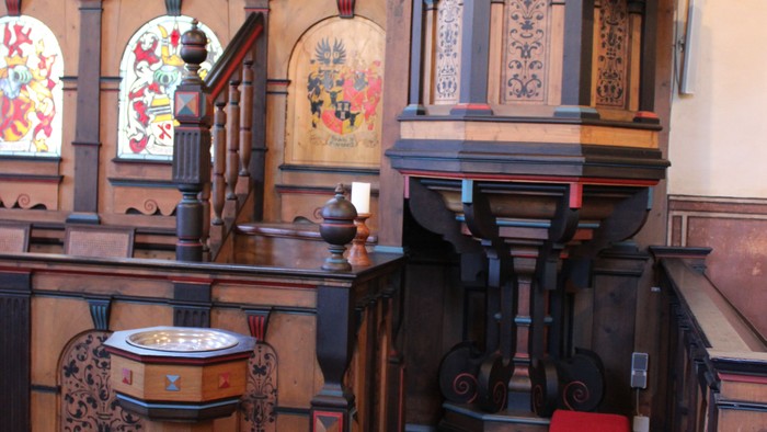 Kircheninneres mit hölzerner Kanzel und Buntglasfenstern