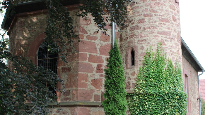 Steingebäude mit Efeu und Bäumen.