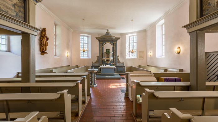 Kleine, helle Kirche mit Holzpulten und Altarraum