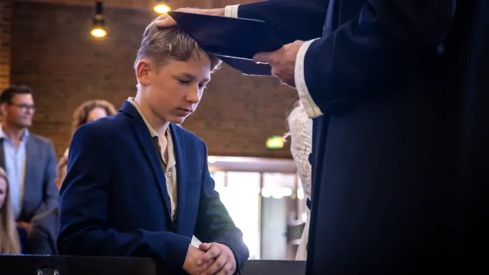 En ung kandidat modtager sin studenterhue fra en embedsmand under en officiel ceremoni.