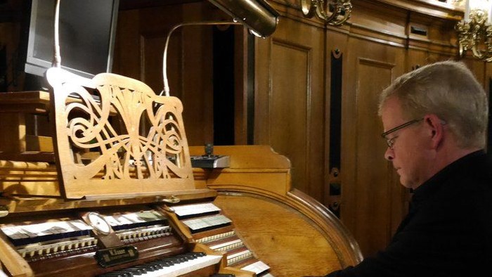 Mand spiller orgel i stue med håndværkede detaljer