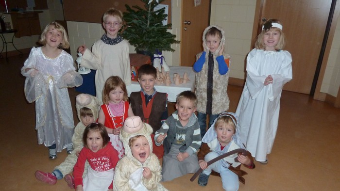 Kinder in Weihnachtskostümen posieren vor Christbaum