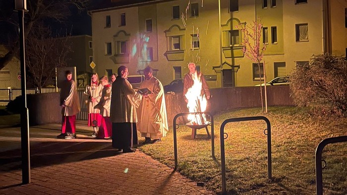 Personen um ein Lagerfeuer im Freien bei Nacht