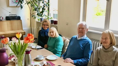 Vier Personen sitzen bei Frühstück in hellem Raum