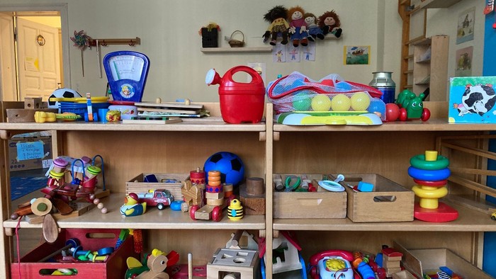 Das Bild zeigt ein Regal mit verschiedenen Spielzeugen und Bastelmaterialien.