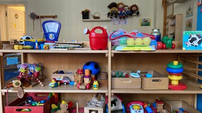 Das Bild zeigt ein Regal mit verschiedenen Spielzeugen und Bastelmaterialien.