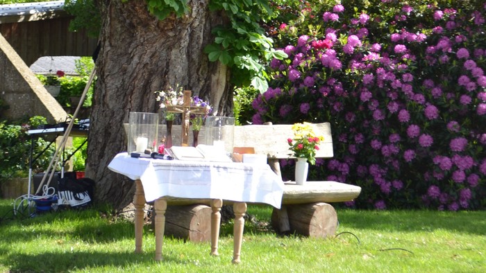 Ein Gartenpicknick-Tisch unter einem Baum mit Blumen und Getränken