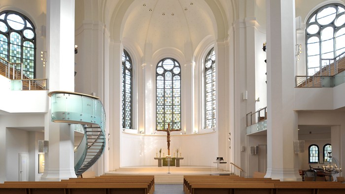 Große, helle Kirche mit hölzernen Bänken und hohen Fenstern